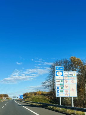 Büyük mavi yol işaretleri ve güneşli bir günde kırsal bir zemin gösteren Polonya otobanını temizleyin.
