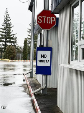 Metal bir binanın yanında mavi MD Vinieta tabelası olan yağmurlu şehir manzarası..