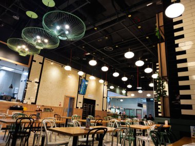 Krakow, Polonya - 12 Ocak 2026: Ahşap masaları, çeşitli sandalyeleri ve güncel yemekler için mükemmel modern dekorları olan geniş bir yemek alanı.