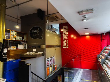 Manchester, İngiltere - 21 Ocak 2026: Konforlu müzik dükkanı titreşimi vinil, CD 'ler ve kırmızı dekoratif bir duvarın yanında raflar