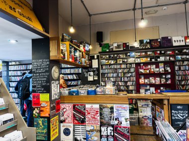 Manchester, İngiltere - 21 Ocak 2026: Plaklar, posterler ve müşterilerle dolu hareketli bir plak dükkanının canlı bir görüntüsü.