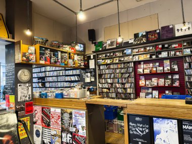 Manchester, İngiltere - 21 Ocak 2026: CD rafları, posterleri ve ahşap kasası olan canlı bir müzik dükkanı sahnesi.