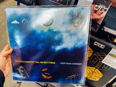 Manchester, İngiltere - 21 Ocak 2026: Ülke havası, kovboy betimlemeleri ve karamsar okyanus resimleriyle birlikte mavi atmosferik vinil kapak. Biz oraya varana kadar Batı Yakası Kovboyu Çok Taşralı