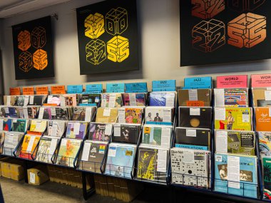 Manchester, İngiltere - 21 Ocak 2026: Bir müzik dükkanında caz ve dünya türlerinin yer aldığı mavi raflarda sıralanmış vinil plaklar.