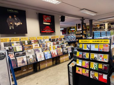 Manchester, İngiltere - 21 Ocak 2026: Kalabalık bir müzik mağazasında vinil plaklar ve parlak tabelalarla dolu rafların geniş görünümü.