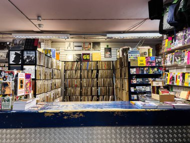 Manchester, İngiltere - 21 Ocak 2026: Vinil, dergi rafları ve mavi bir ön tezgahı olan işlek bir plak mağazası.