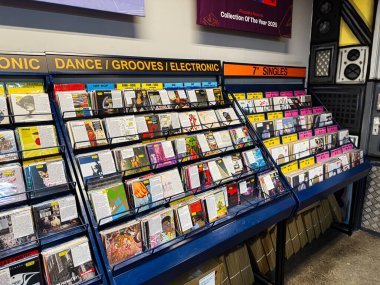 Manchester, İngiltere - 21 Ocak 2026: Bir müzik mağazasında çeşitli türler ve retro titreşimler gösteren açılı raflarda renkli vinil plaklar.