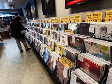Manchester, İngiltere - 21 Ocak 2026: Bir müşteri, Indie Rock kapakları ve sanat eserleriyle dolu işlek bir plak mağazasında plak albümlerine göz gezdirdi.
