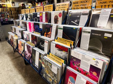 Manchester, İngiltere - 21 Ocak 2026: Yoğun bir plak mağazası renkli vinil kollar ve bağımsız rock ve punk türleri için tabelalar sergiliyor.