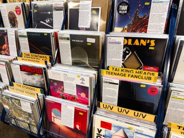 Manchester, İngiltere - 21 Ocak 2026: Sarı etiketli ve tanınabilir sanatçı isimlerine sahip mavi kutulardaki vinil albümler rafı.