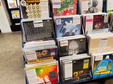Manchester, İngiltere - 21 Ocak 2026: Bir plak dükkanında çeşitli albüm kapakları olan renkli vinil raflar; klasik müzik havası ve retro titreşim.
