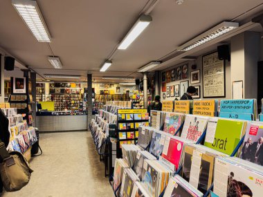 Manchester, İngiltere - 21 Ocak 2026: Albüm rafları, müşterilerin gezinmesi ve renkli ekran işaretleriyle dolu vinil plak mağazası.