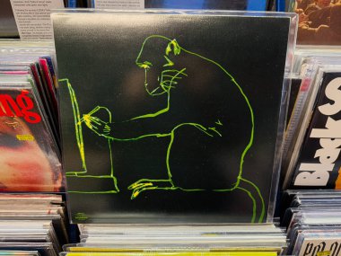 Manchester, İngiltere - 21 Ocak 2026: Bir dükkandaki plak yığınları arasında koyu renkli bir vinil kapak üzerindeki neon yeşil goril illüstrasyonu. Jorge Velez Hayvanlar Diski