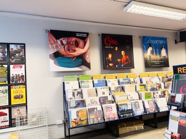 Manchester, İngiltere - 21 Ocak 2026: Vinil rafları, posterleri ve renkli albüm kapakları olan yoğun bir müzik dükkanının geniş görünümü.