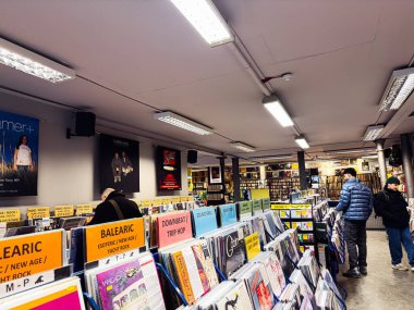 Manchester, İngiltere - 21 Ocak 2026: Müşteriler poster ve müzikle dolu kalabalık bir dükkanda vinil raflarını keşfediyorlar.