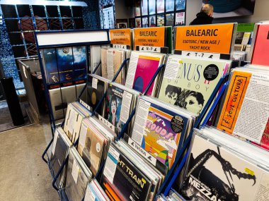 Manchester, İngiltere - 21 Ocak 2026: Parlak turuncu Balearic tabelaları ve çeşitli albüm resimlerinin yer aldığı bir mağazada canlı vinil plaklar sergileniyor.