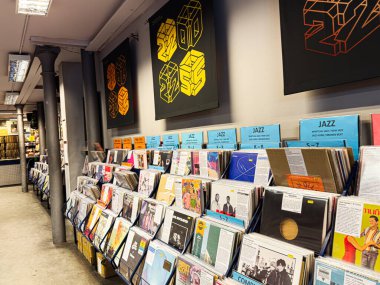 Manchester, İngiltere - 21 Ocak 2026: Caz albümleri, parlak mavi tabelaları ve renkli albüm kapakları olan hareketli bir vinil mağazası.