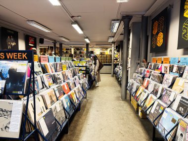 Manchester, İngiltere - 21 Ocak 2026: Müşteriler iyi aydınlatılmış bir dükkanda renkli plak plaklarına göz atarak canlı bir müzik alışveriş sahnesi oluşturdular.