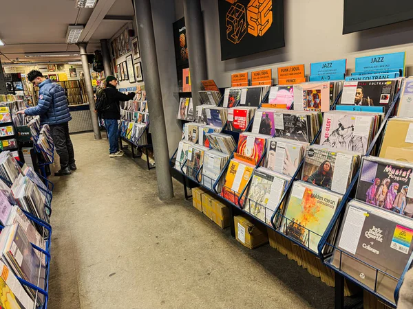 Manchester, İngiltere - 21 Ocak 2026: Alışverişçiler renkli albüm kapakları ve tabelaları olan canlı bir müzik dükkanında vinil rafları keşfediyorlar.