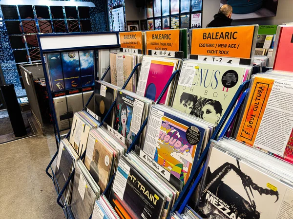 Manchester, İngiltere - 21 Ocak 2026: Parlak turuncu Balearic tabelaları ve çeşitli albüm resimlerinin yer aldığı bir mağazada canlı vinil plaklar sergileniyor.