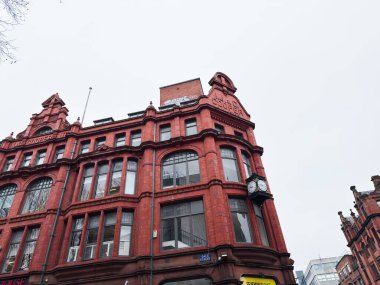 Manchester, İngiltere - 26 Ocak 2026: Büyük pencereli kırmızı tuğlalı Sevendale Binası ve Manchester Dale caddesinde bir saat, tarihi mimari sergilenmektedir.