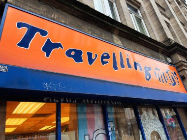 Manchester, İngiltere - 26 Ocak 2026: Manchester 'daki renkli seyahat acentesinin vitrininde koyu turuncu ve mavi tabela, kentsel sokak manzarası.