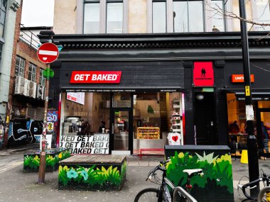Manchester, İngiltere - 26 Ocak 2026: Fırınlanmış Fırın, kentsel sanat ve bisiklet ile Manchester caddesini bir mağazanın önünde bustling.