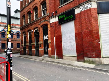Manchester, İngiltere - 26 Ocak 2026: Manchester 'da kırmızı tuğlalı küçük Lever caddesi bisiklet dükkânı ve kapalı panjurlu.