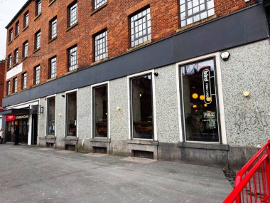 Manchester, İngiltere - 26 Ocak 2026: Manchester 'da sokak seviyesindeki mağazalar büyük cam pencerelerden modern bir kızarmış tavuk kafesinin içini gösteriyor.