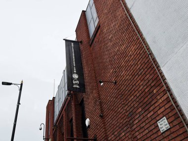 Manchester, İngiltere - 26 Ocak 2026: Tuğla Kurbağa ve Komedi Kulübü ön cephesi Manchester 'da dikey bir afiş, kentsel sokak lambası ve tuğla duvar ile.