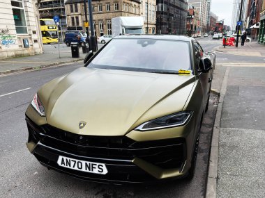 Manchester, İngiltere - 26 Ocak 2026: Manchester caddesinde park etmiş altın renkli bir Lamborghini Urus lüks ve modern şehir tarzını ön plana çıkarıyor.