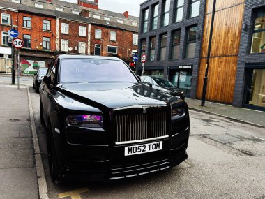 Manchester, İngiltere - 26 Ocak 2026: Parlak siyah bir Rolls-Royce Cullinan SUV Manchester 'da bir şehir caddesinde modern binaların yakınında park halinde..