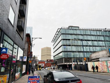 Manchester, İngiltere - 26 Ocak 2026: Camdan binalar, dükkanlar ve yürüyen insanların yer aldığı kalabalık bir Manchester sokak sahnesi.