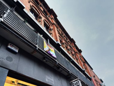 Manchester, İngiltere - 21 Ocak 2026: Balkonları, LGBTQ afişleri ve kentsel vitrinleri olan bir Manchester binasının sokak manzarası.