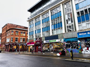 Manchester, İngiltere - 21 Ocak 2026: Grafiti sanatı, renkli dükkan önleri ve ıslak bir kaldırım, canlı enerji.