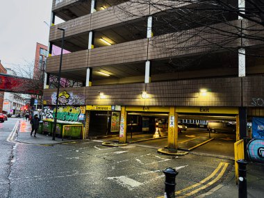 Manchester, İngiltere - 21 Ocak 2026: Yağışlı Manchester UK caddesi ışıklı giriş ve çıkışları olan bir duvar yazısıyla kaplı.