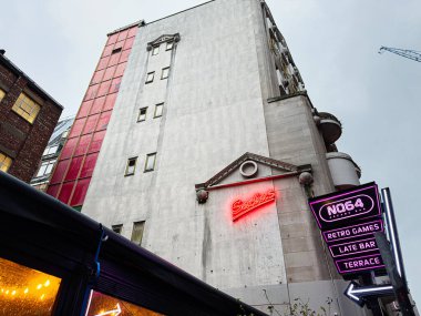 Manchester, İngiltere - 21 Ocak 2026: Manchester kentsel sokak sahnesi nedeki neon NQ64 tabelası, retro oyunları ve gece yarısı barı.