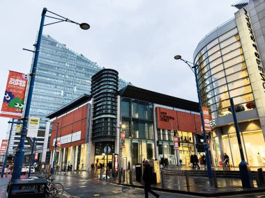 Manchester, İngiltere - 21 Ocak 2026: Modern mağazalar, cam cepheler ve yayalarla dolu Manchester caddesi. Yeni Katedral Sokağı