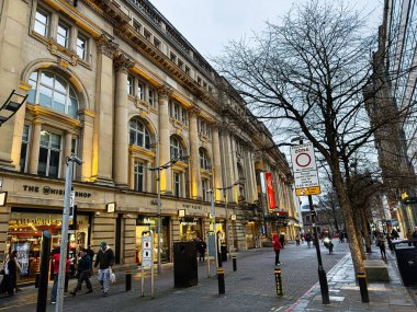 Manchester, İngiltere - 21 Ocak 2026: Tarihi neoklasik binalar, parlak dükkanlar ve yayalar ile Manchester caddesi manzarası.