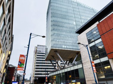 Manchester, İngiltere - 21 Ocak 2026: Cam mimari, caddeler, afişler ve kentsel faaliyetlerin yer aldığı çağdaş Manchester siluet sahnesi.