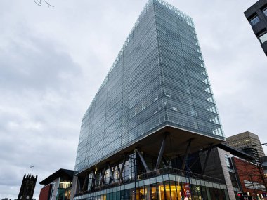 Manchester, İngiltere - 21 Ocak 2026: Sleek glass No. 1 Deansgate kulesi halka açık bir alana bakıyor. Yüksek taban ve dramatik destek sütunları dışarıda..