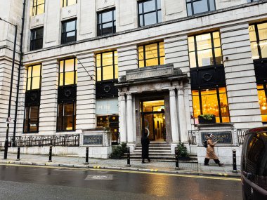 Manchester, İngiltere - 21 Ocak 2026: Manchester Blackfriars Binası 'nın sıcak iç aydınlatmalı tarihi girişi ve yanından geçen insanlar.