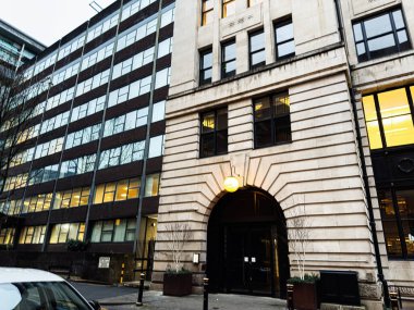 Manchester, İngiltere - 21 Ocak 2026: Taştan kemer girişi, aydınlatma pencereleri ve modern ofis bloklarının yer aldığı çarpıcı Manchester kentsel cephesi.