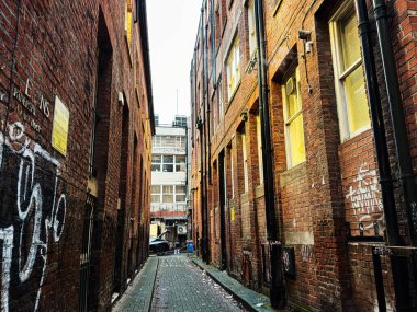 Manchester, İngiltere - 21 Ocak 2026 Grafiti ve tuğla binalarla dolu dar bir patika boyunca Gritty Manchester sokağı.