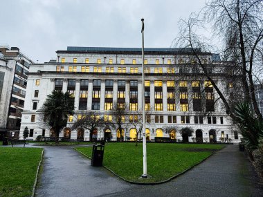 Manchester, İngiltere - 21 Ocak 2026: Büyük beyaz bir Arkwright House binası Manchester UK Parsonage Gardens parkında alacakaranlıkta aydınlatılmış pencereleri olan.