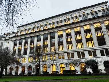 Manchester, İngiltere - 21 Ocak 2026: Parlak pencereleri ve çıplak ağaçları olan görkemli bir Arkwright House Manchester binasının akşam manzarası, neoklasik tarzda.