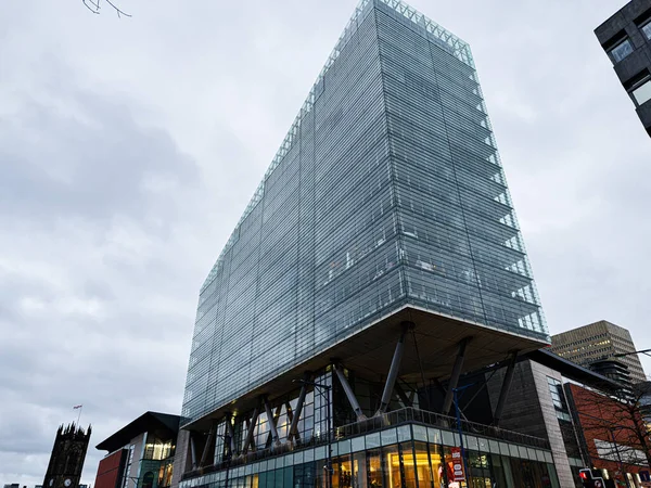 Manchester, İngiltere - 21 Ocak 2026: Sleek glass No. 1 Deansgate kulesi halka açık bir alana bakıyor. Yüksek taban ve dramatik destek sütunları dışarıda..