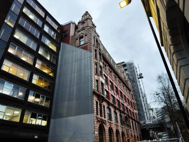 Manchester, İngiltere - 21 Ocak 2026: Manchester City St Mary 's Parsonage Caddesi' nde tarihi kırmızı tuğlalı bina inşa halindeki modern cam kule.
