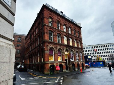 Manchester, İngiltere - 21 Ocak 2026: Manchester yakınlarındaki ıslak bir Manchester caddesindeki kırmızı tuğlalı tarihi bina.