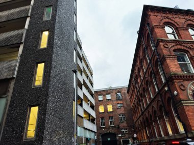 Manchester, İngiltere - 21 Ocak 2026: Kentsel sokak sahnesi modern beton yapının yanında tuğla tarihi bina.